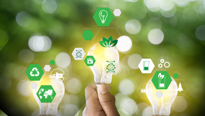 Roka tur spuldzi ar siltu gaismu, bet apkārt redzamas zaļas ekoloģijas un tehnoloģiju ikonas (pārstrāde, DNS, enerģija, daba), kas simbolizē ilgtspējīgu attīstību, inovācijas un zaļo enerģiju uz izplūduša dabas fona.