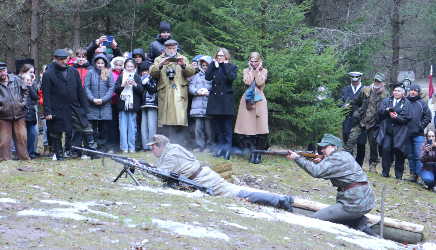Īles nacionālo partizānu bunkura piemiņas vietā organizētā kaujas rekonstrukcija pulcēja plašu interesentu loku gan no Latvijas, gan Lietuvas, tostarp jauniešus. Attēlā notiek kauju rekonstrukcija, kuru vēro apmeklētāji.